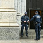 man in black jacket and blue denim jeans standing on gray concrete stairs
