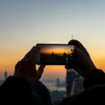 person holding smartphone while taking picture of tower